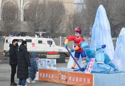 　４日、周囲を装甲車が巡回する広場で、北京冬季五輪の飾りを見る市民＝中国新疆ウイグル自治区ウルムチ（共同）