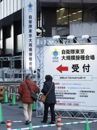 　自衛隊が運営する新型コロナウイルスワクチンの大規模接種会場へ向かう人たち＝７日午前、東京・大手町