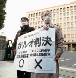 　衆院選の「１票の格差」訴訟の判決を受け、仙台高裁前で「ガリレオ判決」と書かれた紙を掲げる原告側の升永英俊弁護士（右）ら＝８日午後