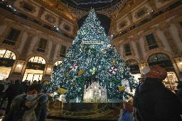 　イタリア・ミラノでクリスマスツリーの近くを通るマスク姿の人々＝昨年１２月２４日（ＡＰ＝共同）