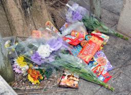 　女児がベランダから転落死した市営住宅に手向けられた花束や菓子＝９日午前、沖縄県名護市