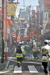 　横浜中華街の火災現場付近で、消火活動をする消防隊員ら＝１１日午前１１時２４分、横浜市