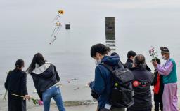 　事故の追悼式で、砂浜から海へ献花する参加者＝１２日午後、山口県宇部市