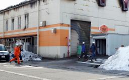 　火災があった「三幸製菓」に入る捜査員ら＝１３日午前９時５０分ごろ、新潟県村上市
