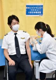 　新型コロナウイルスワクチンの職場接種を受ける全日本空輸のパイロット岩崎雅彦さん（左）＝１４日午前、羽田空港