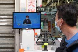 　李家超氏による行政長官選挙出馬会見のテレビ中継を見る人＝９日、香港（ロイター＝共同）