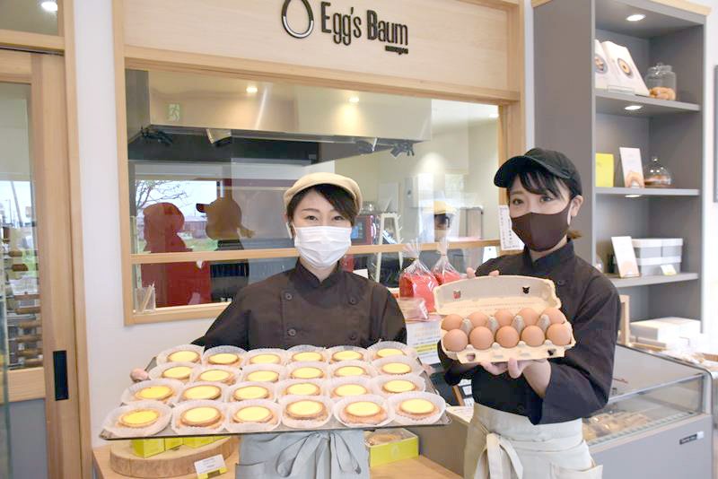 焼きたての香りがほんのり漂う店舗で、自慢の卵を使ったバウムクーヘンを手にする伊藤さん（左）と店長の前田さん＝旭市鎌数
