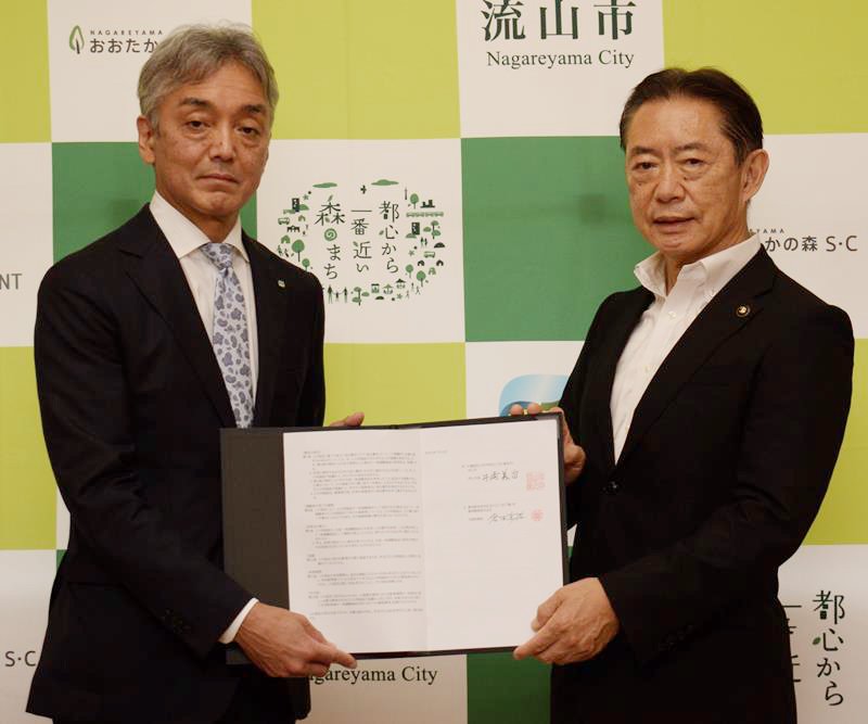 災害時に一時避難施設として駐車場を開放する協定を結んだ東神開発の倉本真祐社長（左）と井崎市長
