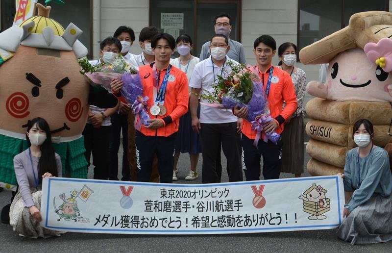 萱選手（前列左から２人目）と谷川選手（同３人目）に花束が手渡され祝福された＝酒々井町役場
