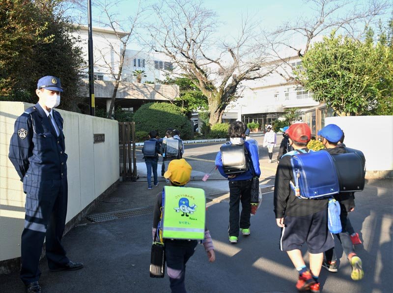 成田署の警察官らが見守る中、登校する成田小の児童＝４日朝、成田市