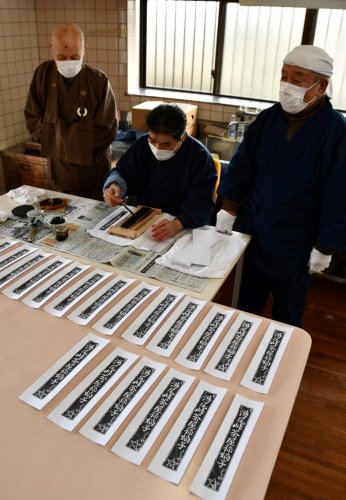 疫病よけお守りを版木から刷る河本さん（中央）と杉浦さん（右）＝柏市
