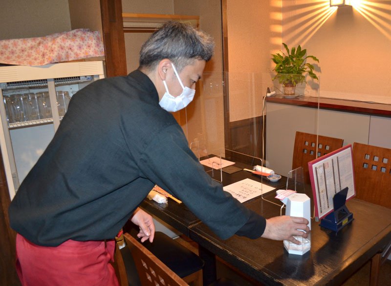 客席に消毒液を設置する根岸さん。重点措置解除で客足の回復に期待を寄せる＝１５日午後３時半ごろ、千葉市中央区
