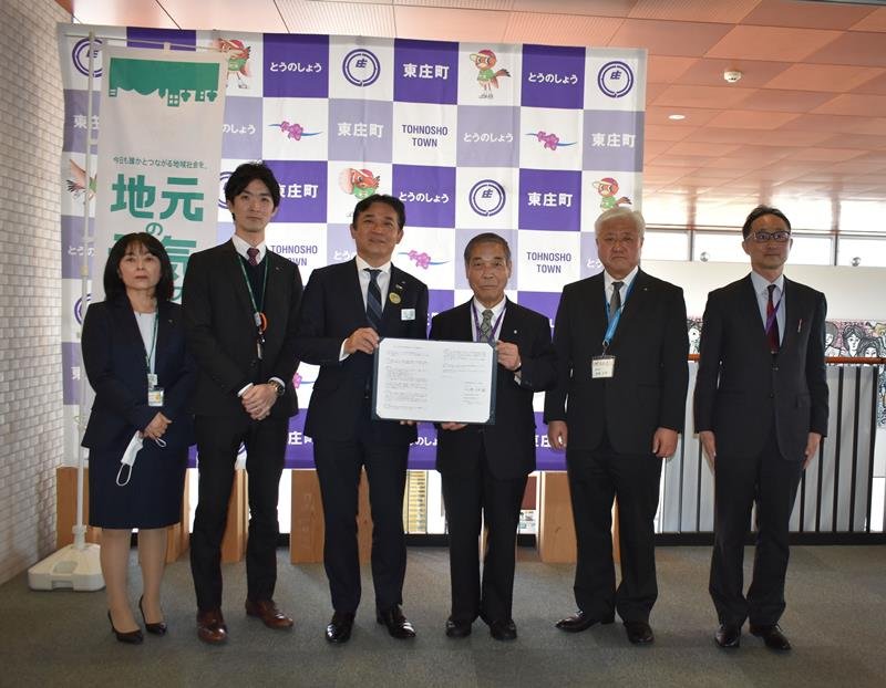 協定書を持つ細井支社長（左から３人目）と岩田町長（同４人目）ら＝東庄町役場
