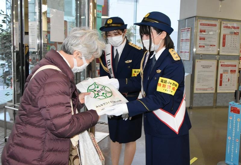 ＡＴＭ前で啓発グッズを配布する一日署長の望月さん（右）と本多さん＝千葉市美浜区
