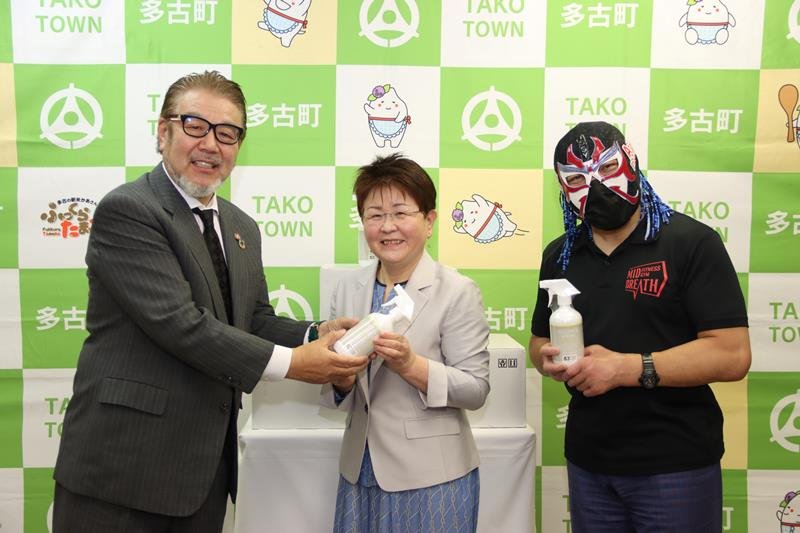 木川教育長（中央）へ消毒液を手渡す荒井会長＝多古町コミュニティプラザ（同町提供）
