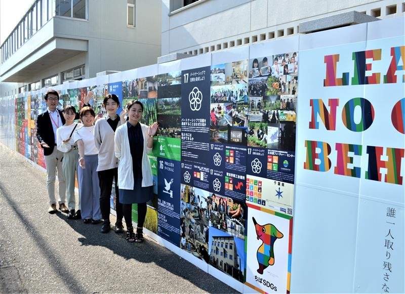 地元団体のＳＤＧｓ活動を紹介する東邦大習志野キャンパスの壁面展示。案内しているのは企画した学生４人と柴田裕希准教授＝船橋市
