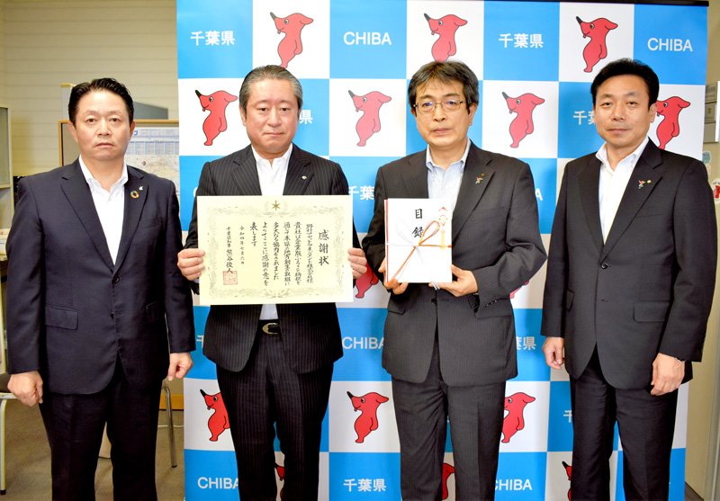 企業版ふるさと納税の贈呈式で、野村アセットマネジメントの鈴木常務執行役員（左から２番目）から目録を受け取った県の高橋総合企画部長（同３番目）＝県庁