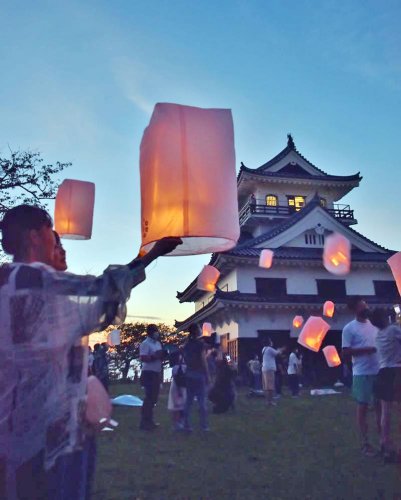 館山城の前で、ＬＥＤランタンを飛ばす参加者＝２７日夜、館山市