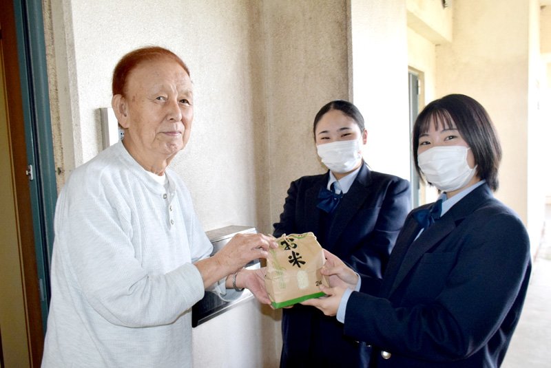 学校の田んぼで実った新米を手渡す旭農業高校の生徒（右）＝旭市