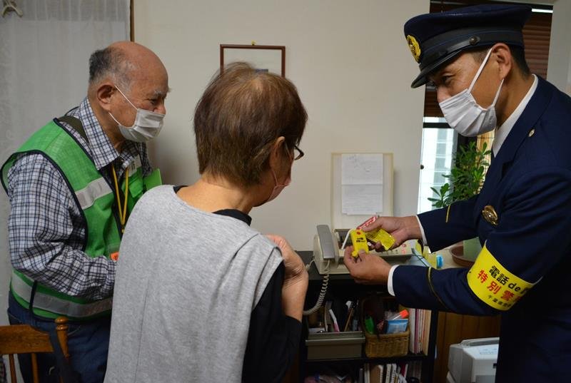高齢者宅を訪れ、詐欺電話の撃退装置を取り付ける船橋署員。この地域に詳しい町会役員も同行した＝１４日、船橋市
