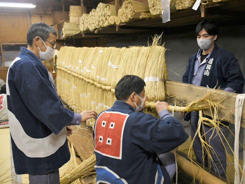 来年の正月に向けて大しめ縄を力いっぱいくくりつける成田山新勝寺の工務員たち＝１日、成田市