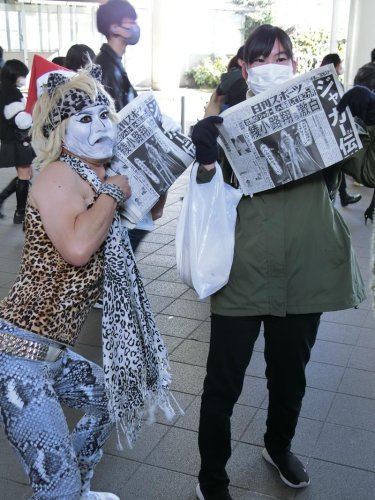 ジャガーさんの「号外」を配布するハローチーターさん（左）と受け取った女性＝２４日、ＪＲ千葉駅前
