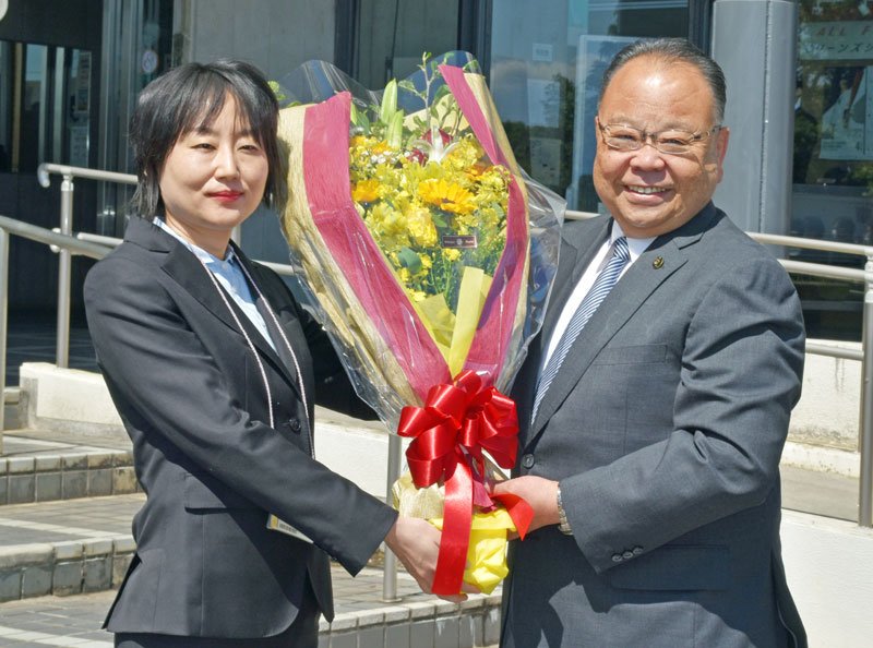 職員から花束を受け取り笑顔を見せる西田市長＝２７日午前、佐倉市役所前