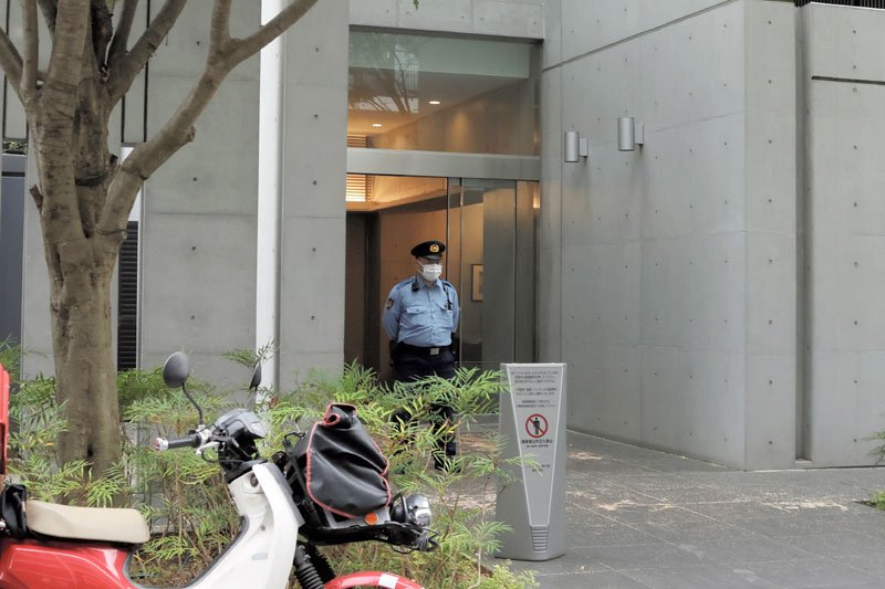 現場マンションのエントランスで警戒する警察官＝２８日午後６時ごろ、市川市