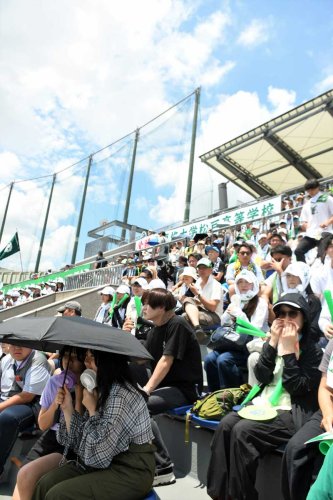 梅雨明けの青空の下、厳しい暑さをしのぎながら高校野球を観戦する人々＝２２日、千葉市稲毛区の県総合スポーツセンター