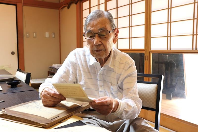 少年兵や捕虜時代から保存していた資料に目を通す春日さん＝香取市

