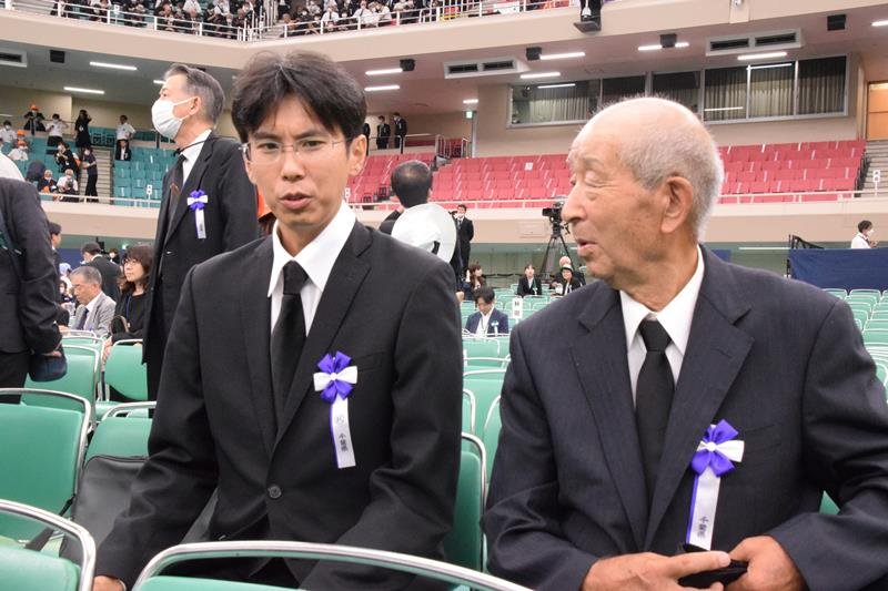 全国戦没者追悼式終了後に言葉を交わす県内最年少参列者の小川さん（左）と最年長の佐藤さん＝１５日、東京都千代田区の日本武道館