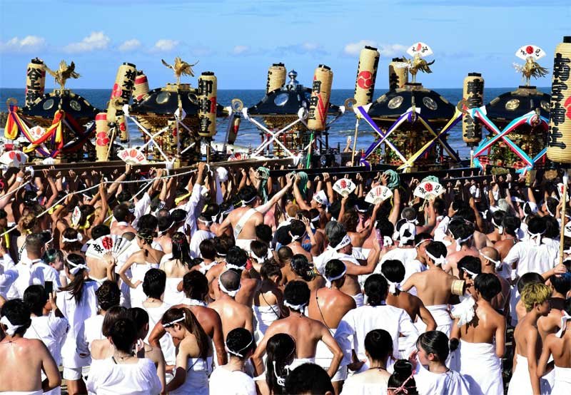 釣ケ崎海岸に集まり神輿を差し上げる担ぎ手＝１３日午後２時５０分ごろ、一宮町