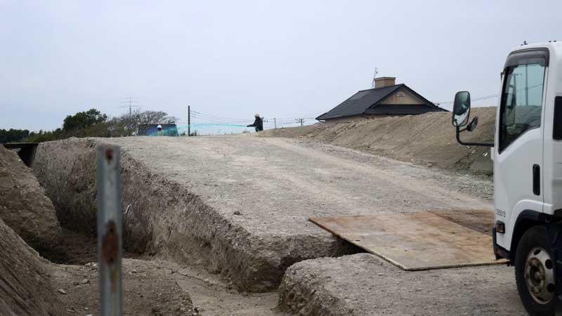 大量の土砂が運び込まれた市有地で飛散防止液を散布する作業員（中央奥）＝５日、山武市小松