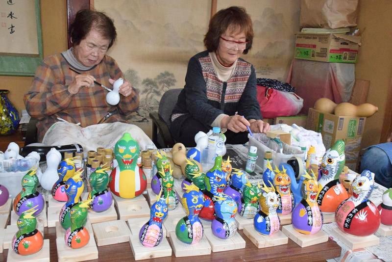 ヒョウタンへの絵付け作業を進める住民たち。来年の主役「辰」の置物が次々に仕上がった＝匝瑳市