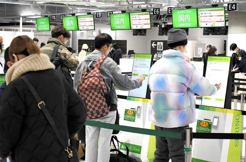 新千歳行きの便に搭乗するため、スプリング・ジャパンの国内線チェックインカウンターに並ぶ旅客＝１０日、成田市の成田空港（画像の一部を加工しています）