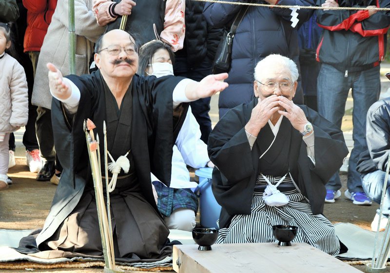 側高神社の伝統の奇祭「ひげなで祭」で、口ひげをなでて新当番に酒を勧める旧当番の氏子＝１４日、香取市
