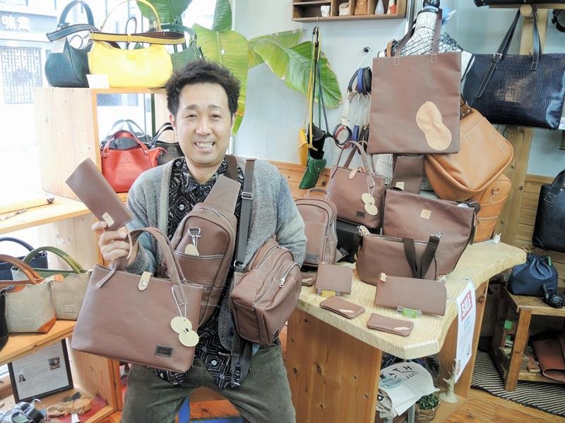 「ピーナッツレザー」を使った商品に囲まれる飯島社長＝柏市
