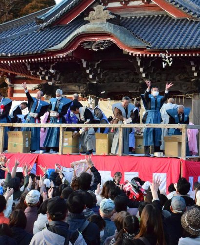 特設の舞台からまかれる豆を取ろうと手を伸ばす来場者＝３日、茂原市の藻原寺
