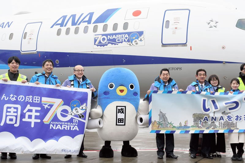 自分のイラスト入りの特別機を紹介するうなりくん（中央）ら＝２３日、成田市の成田空港
