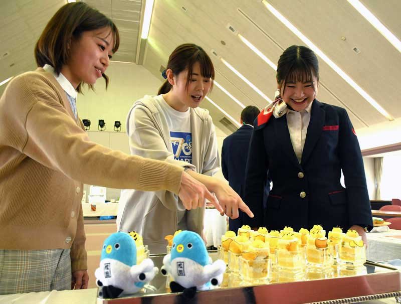 将棋の名人戦で棋士が食べる勝負おやつにエントリーしたスイーツを見る航空会社の地上係員（右）と成田市職員＝市役所