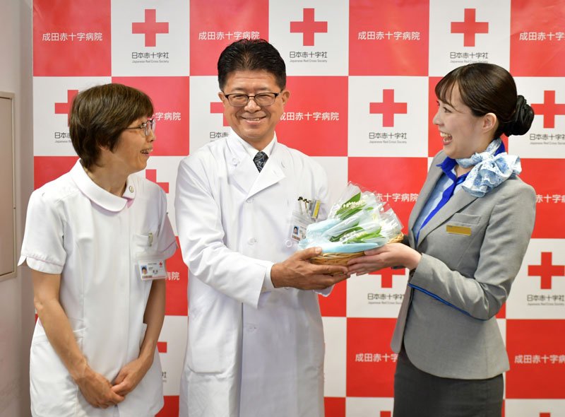 スズランの花束を贈るＡＮＡ客室乗務員の阿部さんと（左から）成田赤十字病院の武田看護部長と渋谷副院長＝成田市