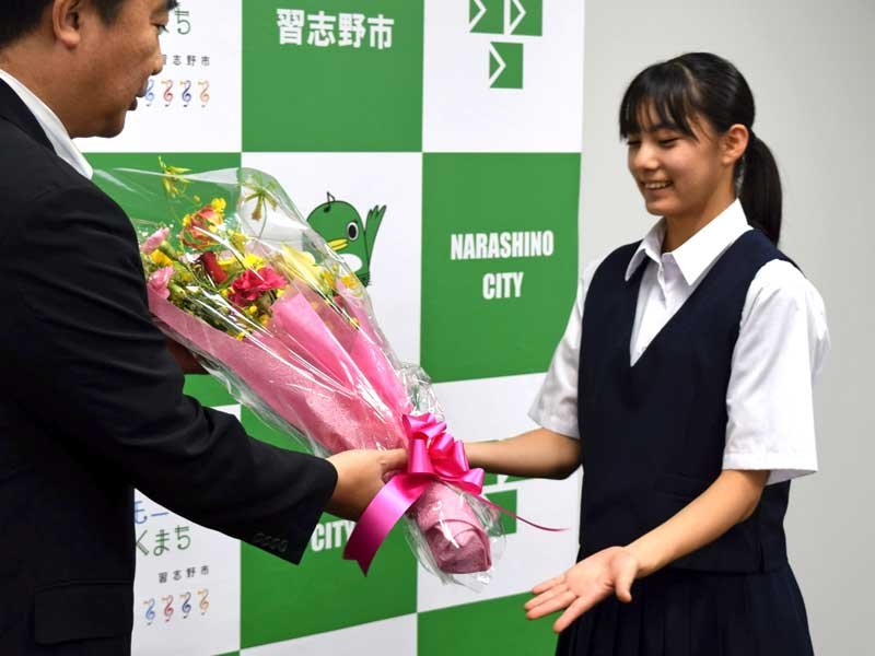 宮本市長（左）から花束を贈られる田久保さん＝習志野市役所