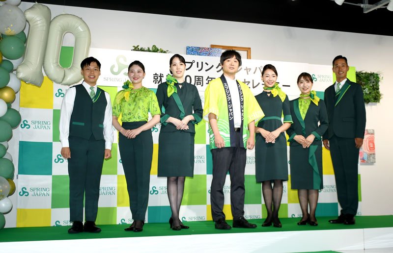 スプリング・ジャパンが就航１０周年となり、節目に合わせて刷新された制服を披露する客室乗務員と浅見社長（中央）＝１日、成田市の成田空港