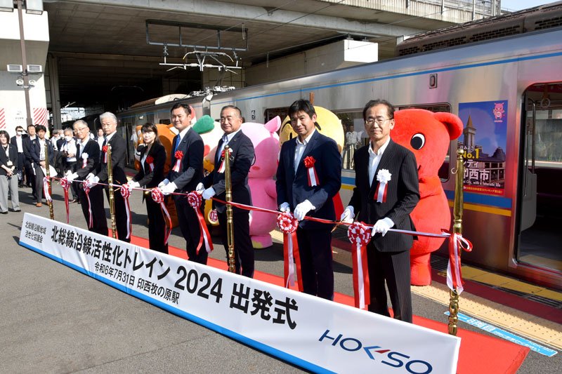 ラッピング電車「北総線沿線活性化トレイン」の出発式で車両を背にテープカットした沿線市長ら＝印西市の印西牧の原駅