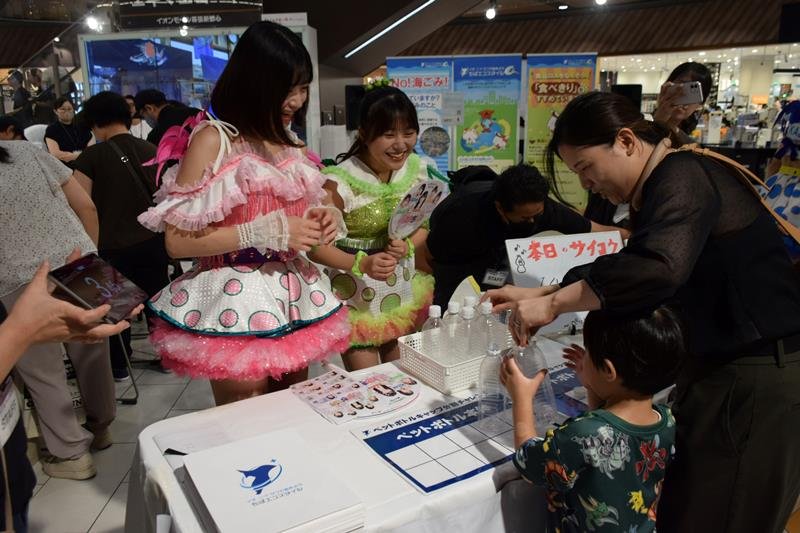 アイドルと一緒にペットボトルのキャップ外し競争にチャレンジする親子ら＝千葉市美浜区のイオンモール幕張新都心
