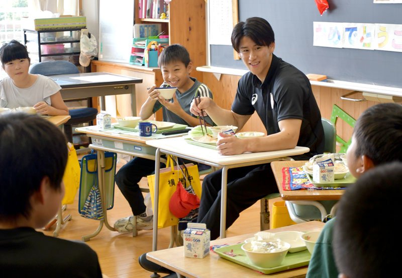 下総みどり学園の児童に囲まれて給食を楽しむ橋本選手（右奥）＝１２日、成田市