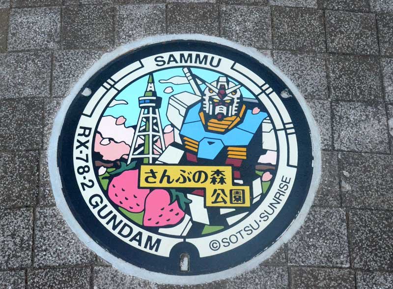 「さんぶの森公園」に設置されたマンホール。ガンダムやイチゴ、同公園のシンボルである「グリーンタワー」が描かれている＝山武市
