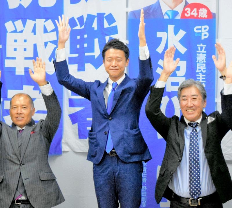 初当選を決め万歳する立憲民主党の水沼氏（中央）＝２７日、船橋市