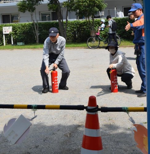 練習用の消火器で使い方を確認する来場者ら＝船橋市
