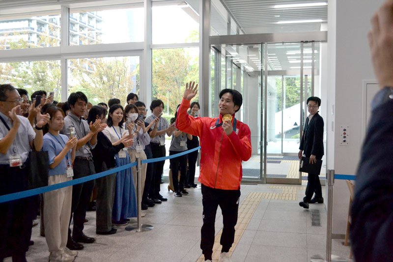 拍手で出迎えられる萱選手＝４日、千葉市役所